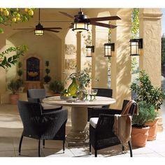 an outdoor dining area with chairs and a table in the middle, surrounded by potted plants