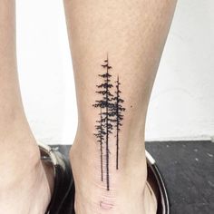 a small pine tree tattoo on the left ankle is shown in black ink, and it's surrounded by smaller trees