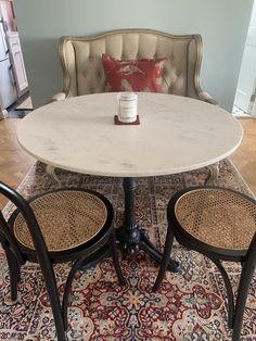 a white table with two chairs and a red pillow on the floor in front of it