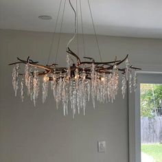 a chandelier made out of branches and glass beads hanging from it's ceiling