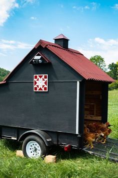 a small black shed with two chickens in it