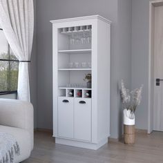 a white cabinet with wine glasses on it in a living room next to a window