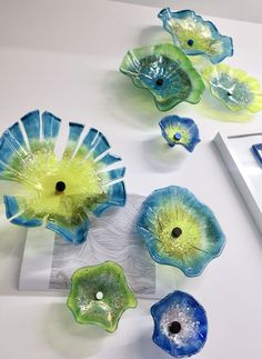 four blue and green glass flowers sitting on top of a table