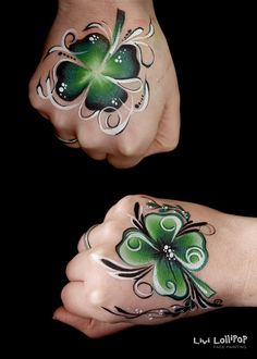 two hands painted with green and white designs, one holding the other's hand