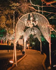 an archway decorated with lights and hanging from it's sides in a park at night