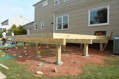 some people are working on building a house in the back yard with wood beams and concrete