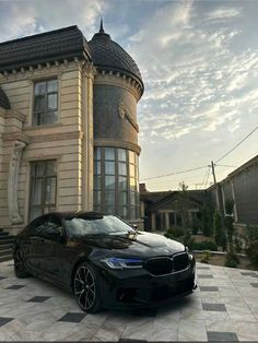 a black car is parked in front of a large house on a checkered floor