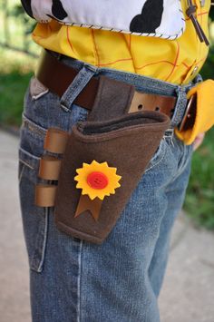 a person wearing a cow print shirt and jeans holding a belt with a flower on it