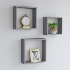 three square shelves with two clocks and a potted plant