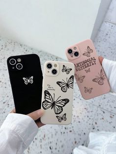 two cases with butterflies on them are being held up by someone's hand in front of the camera