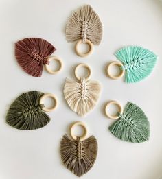 six rings with tassels in different colors on a white plate next to each other