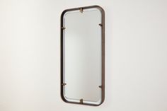 a mirror hanging on the wall with metal bars and rivets around it's edges