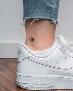 a woman's foot with a small palm tree tattoo on her left side ankle