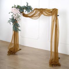 a wedding arch decorated with flowers and greenery on the floor in front of a white wall