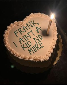 a heart shaped cake with a lit candle in it that says frank's i am not a kid no more