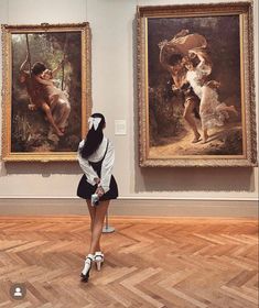 a woman standing in front of two paintings