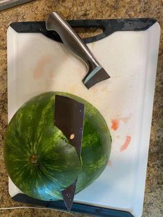 a watermelon on a cutting board with a knife