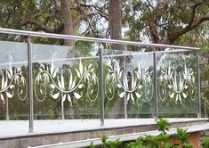 a metal fence with flowers etched on the glass and trees in the backround