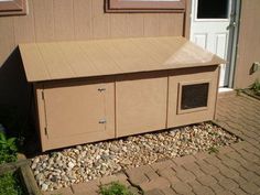 a dog house sitting on the side of a building next to a brick walkway and door