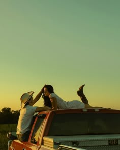 two people sitting on the back of a pick up truck with their feet in the air