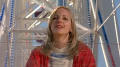 a woman standing in front of a ferris wheel with her eyes closed and looking up