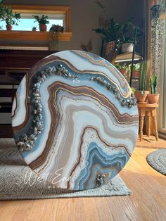 a blue and white marble sculpture sitting on top of a wooden floor next to a potted plant