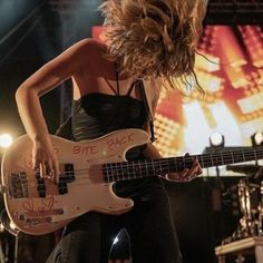 a woman with long hair playing an electric guitar