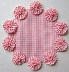 a pink and white checkered table cloth with flowers on the center, surrounded by smaller pink buttons