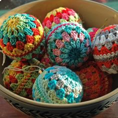 a bowl filled with crocheted balls on top of a wooden table