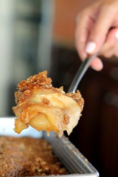 a person holding a fork with some food on top of it and another piece of cake in the background