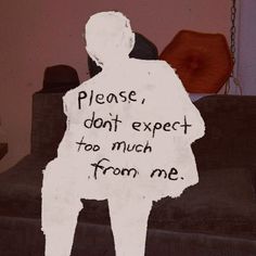 a person standing in front of a couch with a sign that says please, don't expect too much from me