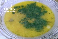 a glass bowl filled with yellow soup and parsley