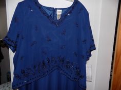 a blue top with sequins is hanging on a hanger in front of a door