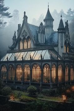 a large building with lots of windows in the middle of some trees and foggy sky