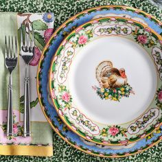 a plate with a turkey on it next to silverware and forks, napkins