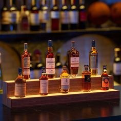 several different types of liquor are lined up on a wooden shelf in front of bottles