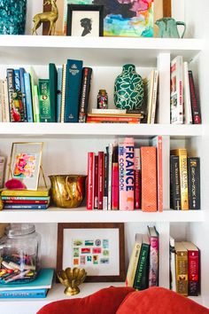 a bookshelf filled with lots of books next to a vase and other items