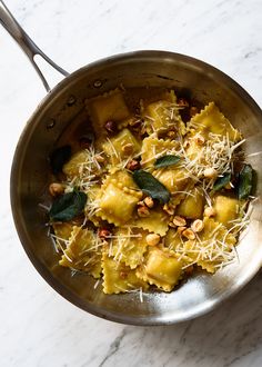 pasta with spinach, pine nuts and parmesan cheese in a silver pan