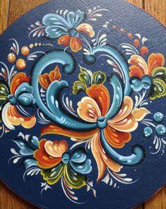 an artistically painted blue and orange plate on a wooden table