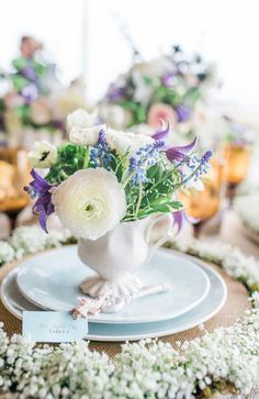 a white vase filled with flowers sitting on top of a table next to other plates