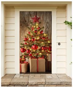 a decorated christmas tree in front of a door with presents under it and an ornament hanging from the top