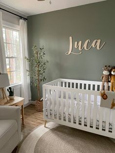 a baby's room with green walls and white furniture