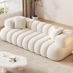 a large white couch sitting on top of a living room floor next to a window