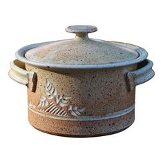 a brown and white pot with leaves on the lid is sitting in front of a white background