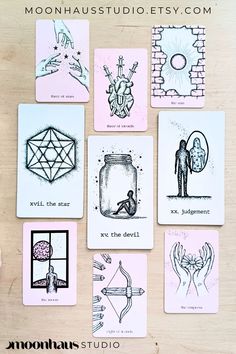 nine cards with different designs on them sitting on a table next to a pen and ink drawing