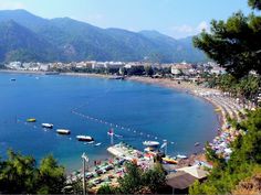 the beach is crowded with people and boats