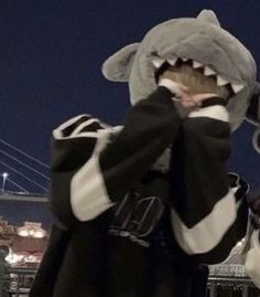 a man in a shark costume standing next to a fence with his mouth wide open