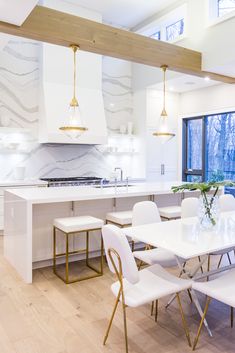 a large kitchen with white chairs and marble counter tops, along with an island in the middle