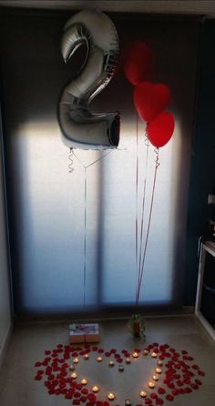 two balloons are floating in the air next to a heart - shaped table with candles