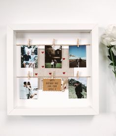 a white frame with pictures hanging on clothes pins and photos attached to the pegs